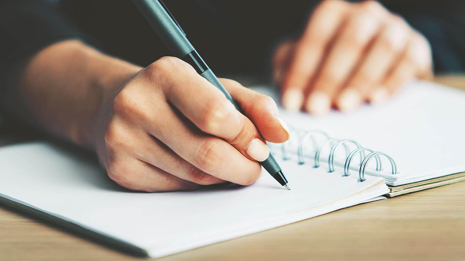 person writing on a notebook