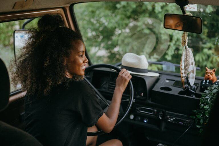 Free Woman driving a van through nature, enjoying a summer road trip journey. Stock Photo